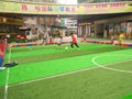 Boys playing soccer inside a shopping mall in a indoor soccer field.