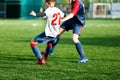 Boys in red and blue sportswear plays football on field, dribbles ball. Young soccer players with ball on green grass. Royalty Free Stock Photo