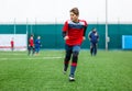 Boys in red white sportswear running on soccer field. Young footballers dribble and kick football ball in game. Training