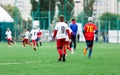 Boys in red white sportswear running on soccer field. Young footballers dribble and kick football ball in game. Training