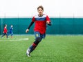 Boys in red white sportswear running on soccer field. Young footballers dribble and kick football ball in game. Training