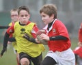 Boys with red/yellow jacket play rugby