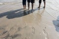 Boys with rolled up paint on the wet sandy beach footprint on wet sand and feet