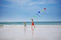 Boys run holding many colorful kite at beach smiling side view Royalty Free Stock Photo