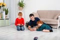 The boys sit on the floor in the room and play with the machine with the remote control Royalty Free Stock Photo