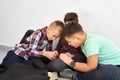 Boys sitting on floor and playing game on smartphone. Royalty Free Stock Photo