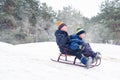 Boys sledding in a snowy forest. Outdoor winter fun for Christmas vacation.