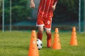 Boys on soccer football training. Young players dribble ball between training cones