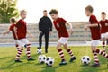 Boys in Soccer Jersey Kits Kicking Soccer Balls on Training Session. Young Football Coach Teaching School Kids Royalty Free Stock Photo