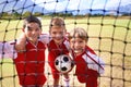 Boys, soccer player and ball on goal net, smile and happy for game, field and child. Outdoor, playful and sport for Royalty Free Stock Photo
