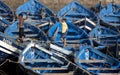 Boys stand amongst the many fishing boats in the port of Essouaira, Morocco.