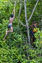 Boys swinging from a tree into the Madu River at Balapitiya in Sri Lanka.