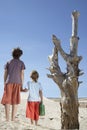 Boys With Watering Can Standing By Dead Tree Royalty Free Stock Photo