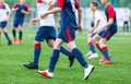 Boys in white and blue sportswear plays football on field, dribbles ball. Young soccer players with ball on green grass. Training Royalty Free Stock Photo