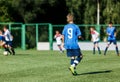 Boys in white and blue sportswear plays football on field, dribbles ball. Young soccer players with ball on green grass.