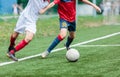 Boys in white and red sportswear plays football on field, dribbles ball. Young soccer players with ball on green grass. Training, Royalty Free Stock Photo