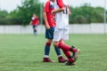 Boys in white and red sportswear plays football on field, dribbles ball. Young soccer players with ball on green grass. Training, Royalty Free Stock Photo