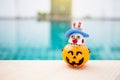 Bozo ghost wooden doll in Halloween pumpkin lantern with space on swimming pool background