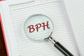 BPH Benign Prostatic Hyperplasia word. BPH word as medical concept. BPH through a magnifying glass on a notepad page Royalty Free Stock Photo