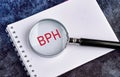 BPH Benign Prostatic Hyperplasia. BPH written through a magnifying glass on a blank piece of notebook Royalty Free Stock Photo