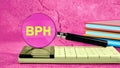 BPH Benign Prostatic Hyperplasia. BPH written through a magnifying glass standing on a calculator in bright colors Royalty Free Stock Photo