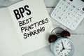 BPS Best Practices Sharing text on paper notebook page with alarm clock and calculator on wooden background Royalty Free Stock Photo
