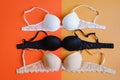 Bra of white, black and beige color on orange and yellow background, overhead view Royalty Free Stock Photo