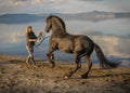 Girl and trained black stallion on the shores of Lake Bracciano in Lazio, Italy