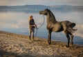 Girl and trained black stallion on the shores of Lake Bracciano in Lazio, Italy