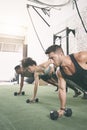 Brace your core and tighten your hips. a fitness group using dumbbells while doing push-ups at the gym. Royalty Free Stock Photo