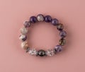 Bracelet made of amethyst and quartz,. A bracelet made of natural stones on the hand. Handmade jewelry on a pink Royalty Free Stock Photo