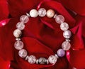 a bracelet made of semi-precious stones of different colors on the petals of red roses. Royalty Free Stock Photo