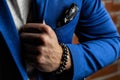 Bracelets mascots of precious stones and minerals on a hand, in a blue business suit on a brick wall background Royalty Free Stock Photo