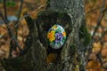 Braided egg with beads with a pattern of purple flowers. On a stump in the park. Needlework, blank Royalty Free Stock Photo