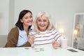 Energetic elder woman and caregiver picking up puzzle