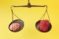 Brain and heart on scale balance on yellow background