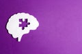 Brain paper symbol with a puzzle piece cut out on the purple background. Mental health symbol Royalty Free Stock Photo