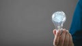 Brain-shaped filament illuminated inside a glass light bulb held by a hand, symbolizing a bright idea Royalty Free Stock Photo