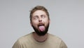 Brainless dumb cheerful bearded guy showing tongue out, looking cross eyed and aping as fool, behaving childish