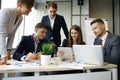 Brainstorm. Group of business people looking at the laptop together. One business woman looking at camera.