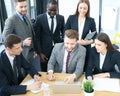 Brainstorm. Group of business people looking at the laptop together. One business woman looking at camera.