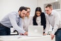 Brainstorm. Group of cheerful business people in smart casual wear looking at the laptop together and smiling