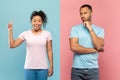 Brainstorming. Pensive black man thinking about question and touching chin, woman having idea, pink and blue background