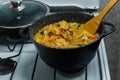 Braised eggplant with meat and Israeli rice in a cast-iron high frying pan on the stove.