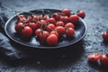 Branch of cherry tomatoes on black plate, close up. Selective focus Royalty Free Stock Photo