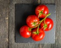 Branch with five ripe red tomatoes. Drops of water on ripe fruits. Green leaves and trunk. Royalty Free Stock Photo