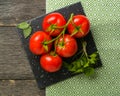 Branch with five ripe red tomatoes. Drops of water on ripe fruits. Green leaves and trunk. Royalty Free Stock Photo