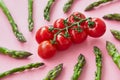 A branch of fresh cherry tomatoes in the center of spiral rays made with asparagus