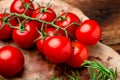 Branch of fresh cherry tomatoes with greens on a brown wooden background Royalty Free Stock Photo