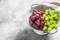 A branch of red and green grapes in a colander. Gray background. Top view. Copy space Royalty Free Stock Photo